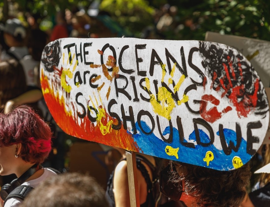 Image of a protest sign that says The Oceans are rising, so should we