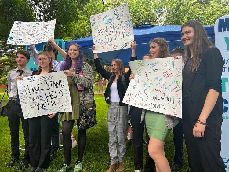 young people hold signs in Montana saying "We stand with Held Youth"