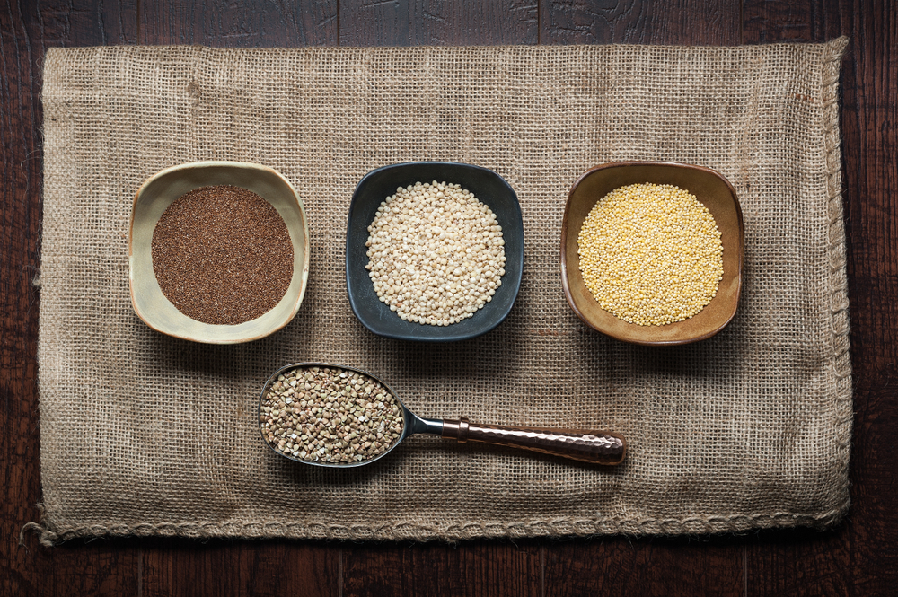 Sorghum, millet, and teff are ancient grains, in bowls on canvas.