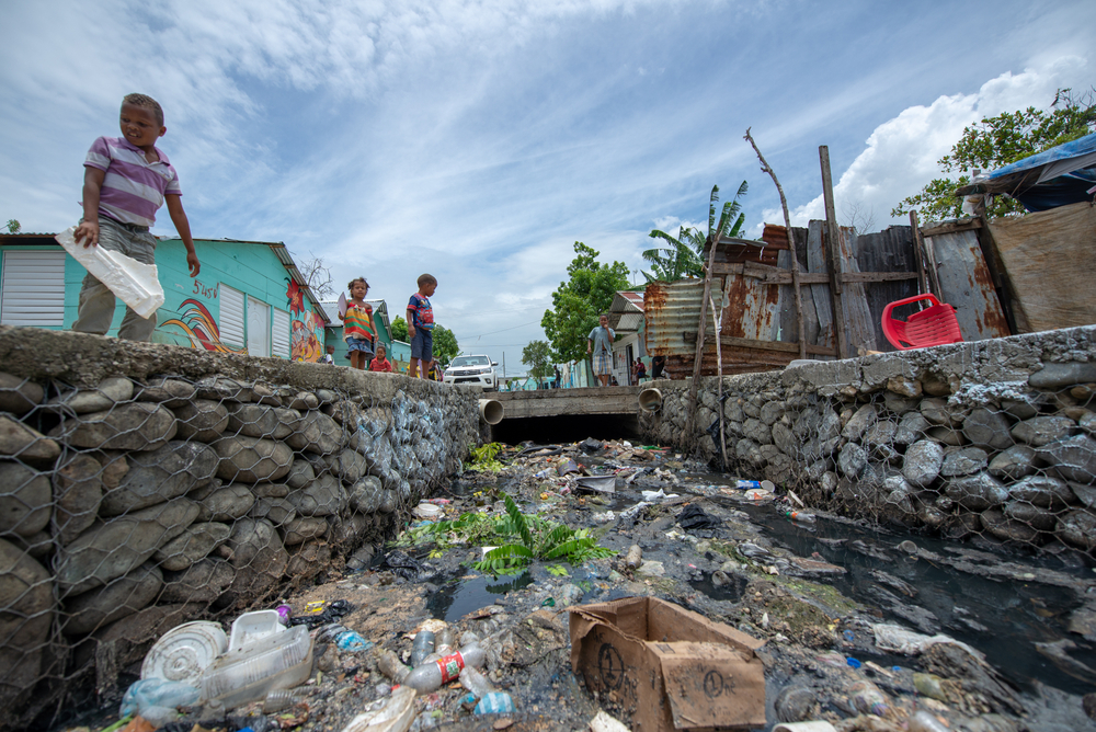 Poor hildren in Santo Domingo play by an aqueduct with waste dumped