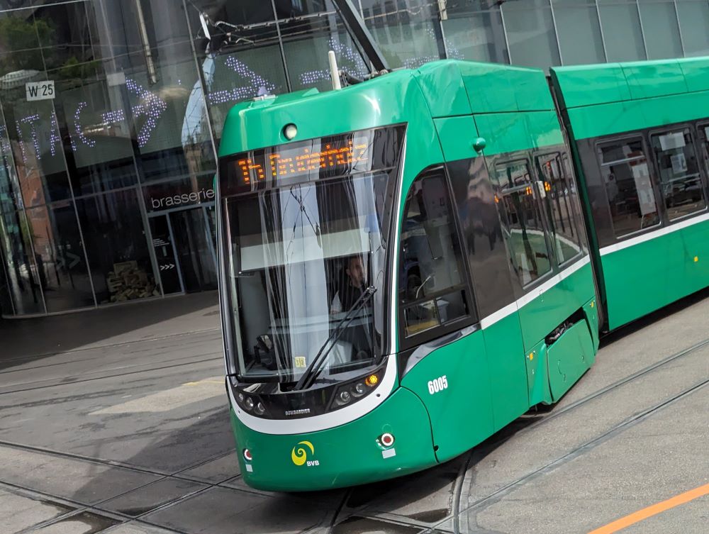 A sleek green tramway train on the track in downtown Basel, Switzerland is a major contributor to climate action solutions.