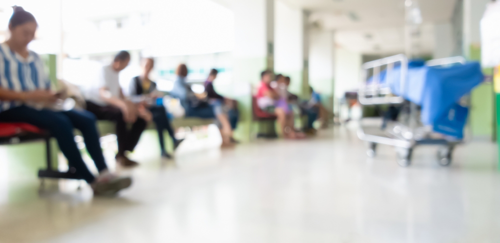 Blurrred image of patients waiting in Hospital emergency room, with wheeled stretcher in foreground
