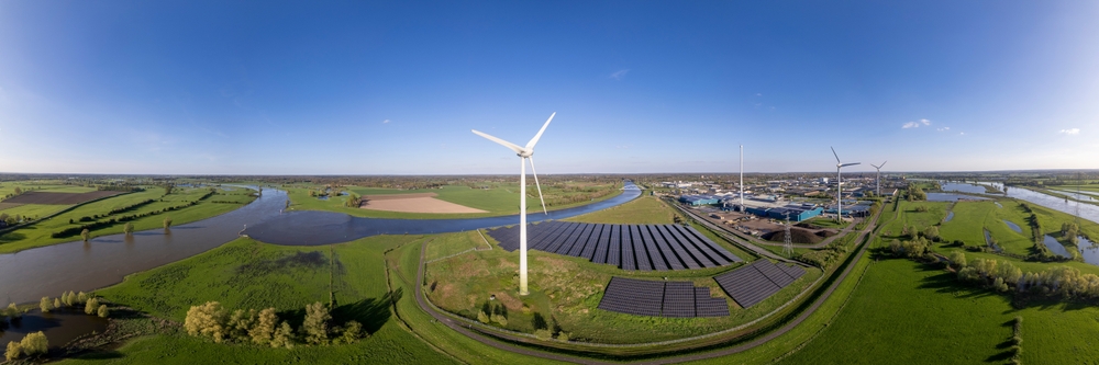 Windmills, solar panels, sustainable energy landscape set in green fields