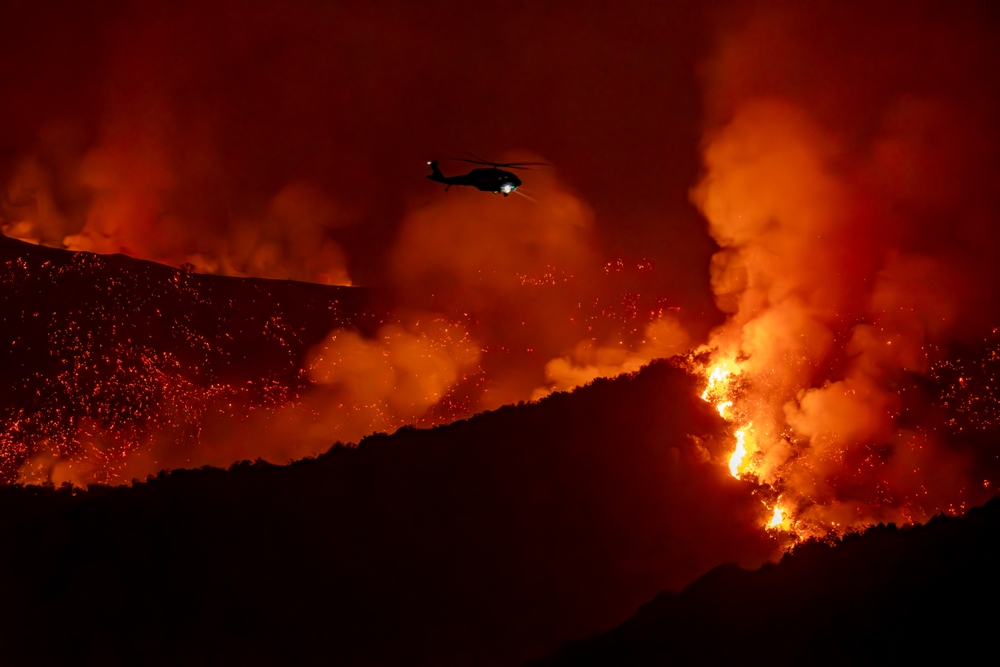 Image of helicopter above blazing wildfires near Los Angeles in 2025